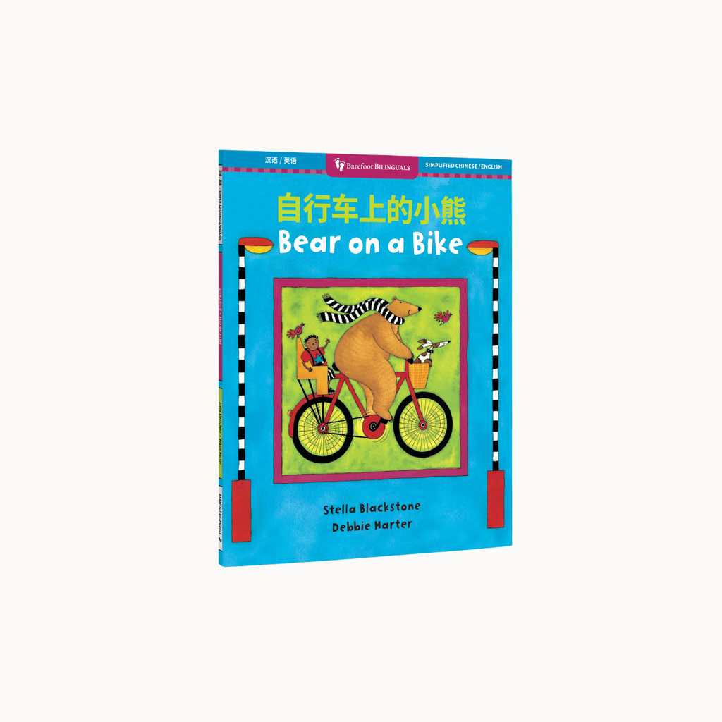 Children's book titled "Bear on a Bike" with Chinese text at the top, shown standing upright against a plain white background. The cover is bright blue with a central illustration of a bear riding a bicycle and colorful accents.