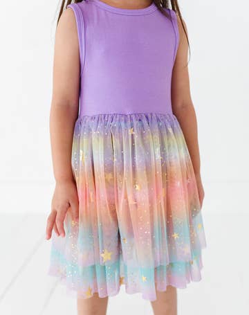 Child wearing a purple top and colorful star-patterned skirt on a white background