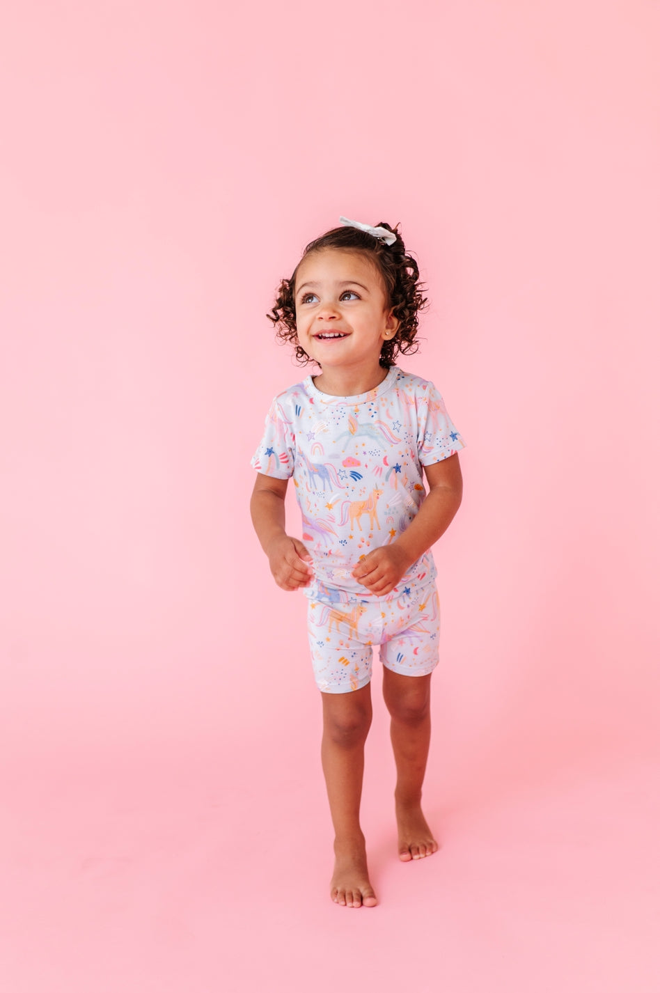 Child wearing a colorful pajama set on a pink background