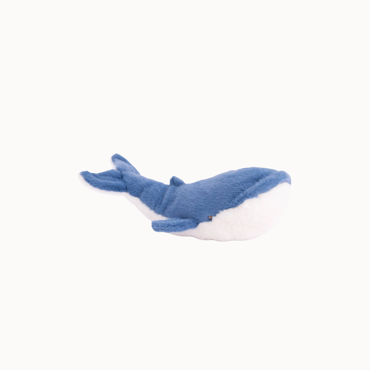A small plush whale toy in blue and white, photographed on a clean off-white background.