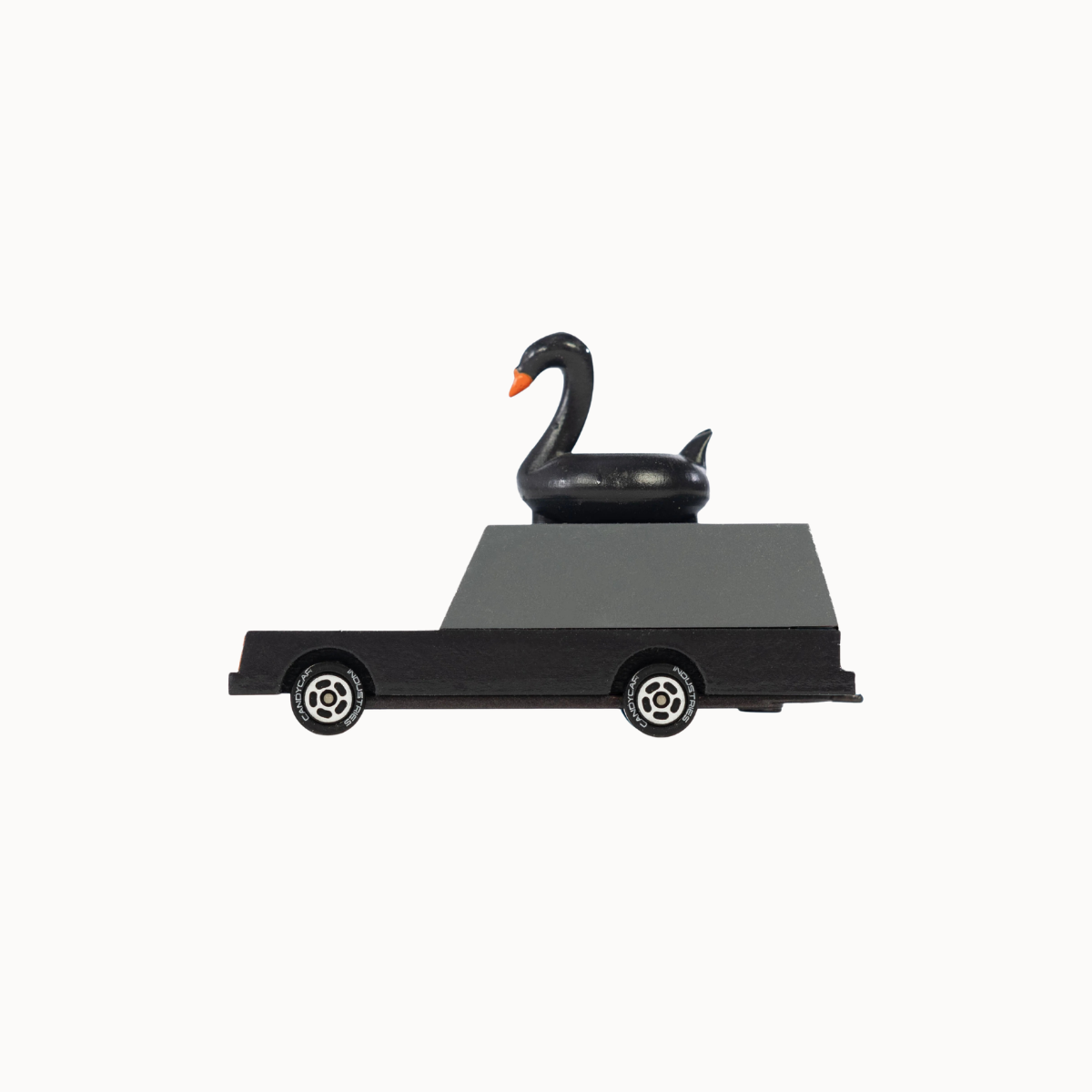 A black toy car with a glossy black swan figurine sitting on its flatbed, set against a plain off-white background.
