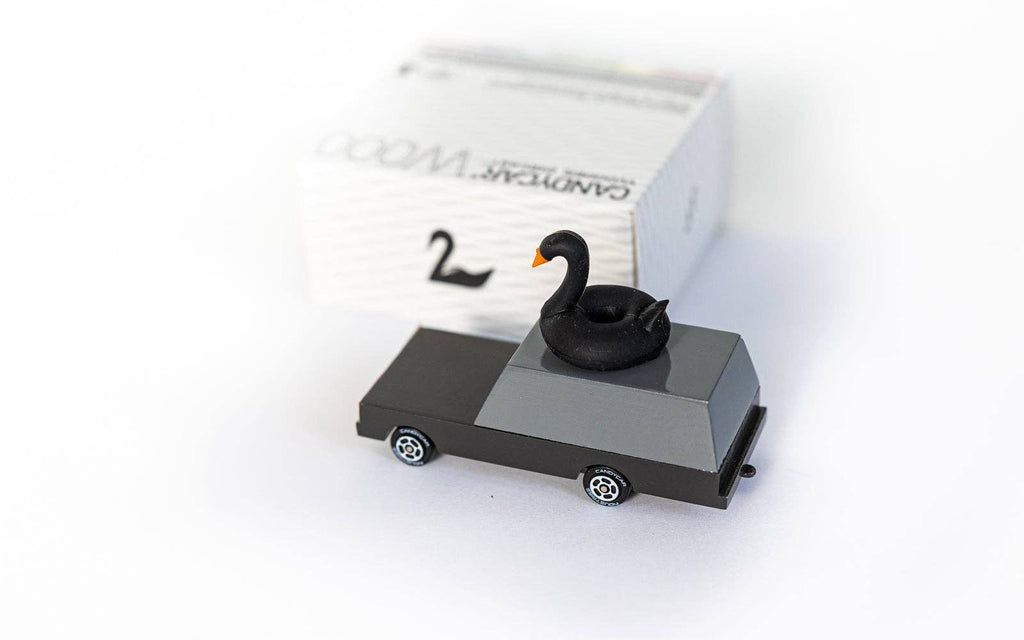 Model of a car with a swan on top, placed on a white surface.