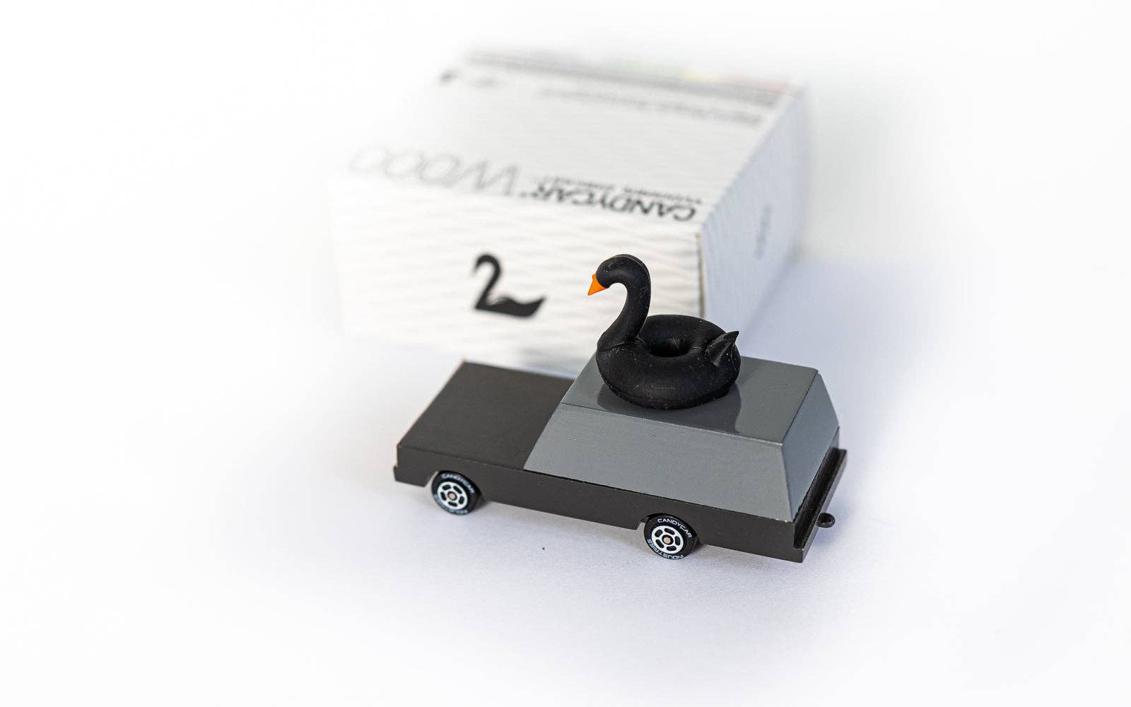 Model of a car with a swan on top, placed on a white surface.