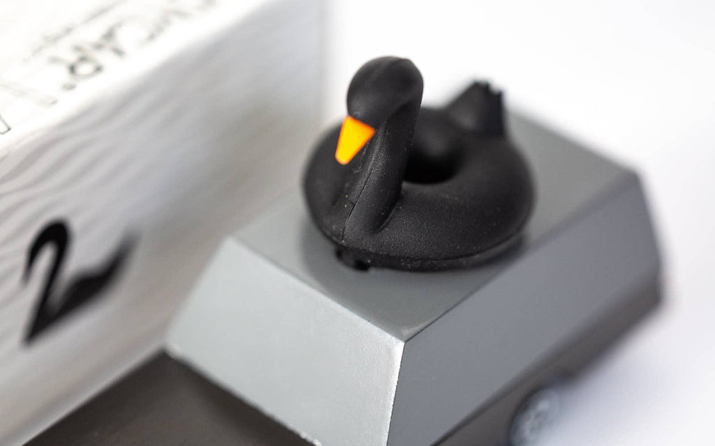 Black rubber duck on a white surface with a close-up view