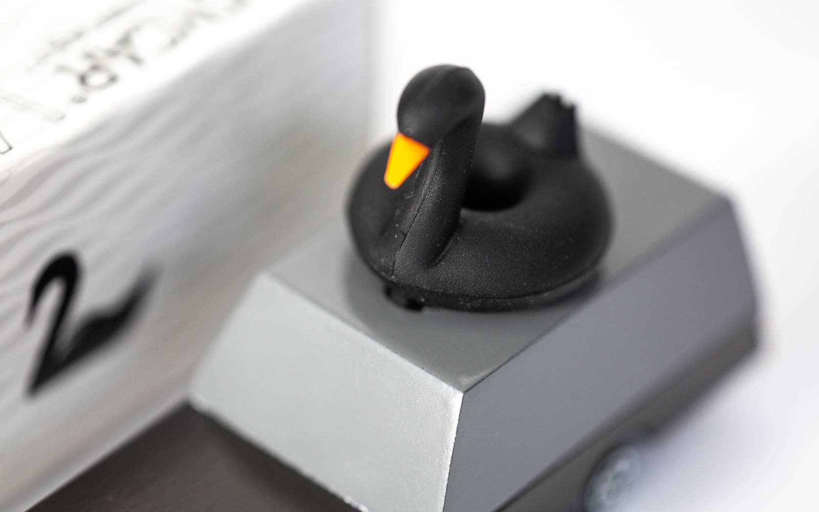 Black rubber duck on a white surface with a close-up view