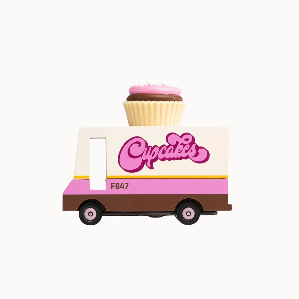 A small toy food truck with a cupcake on top, featuring pink, cream, and brown colors with the word 'Cupcakes' on the side, shown on a plain light background.