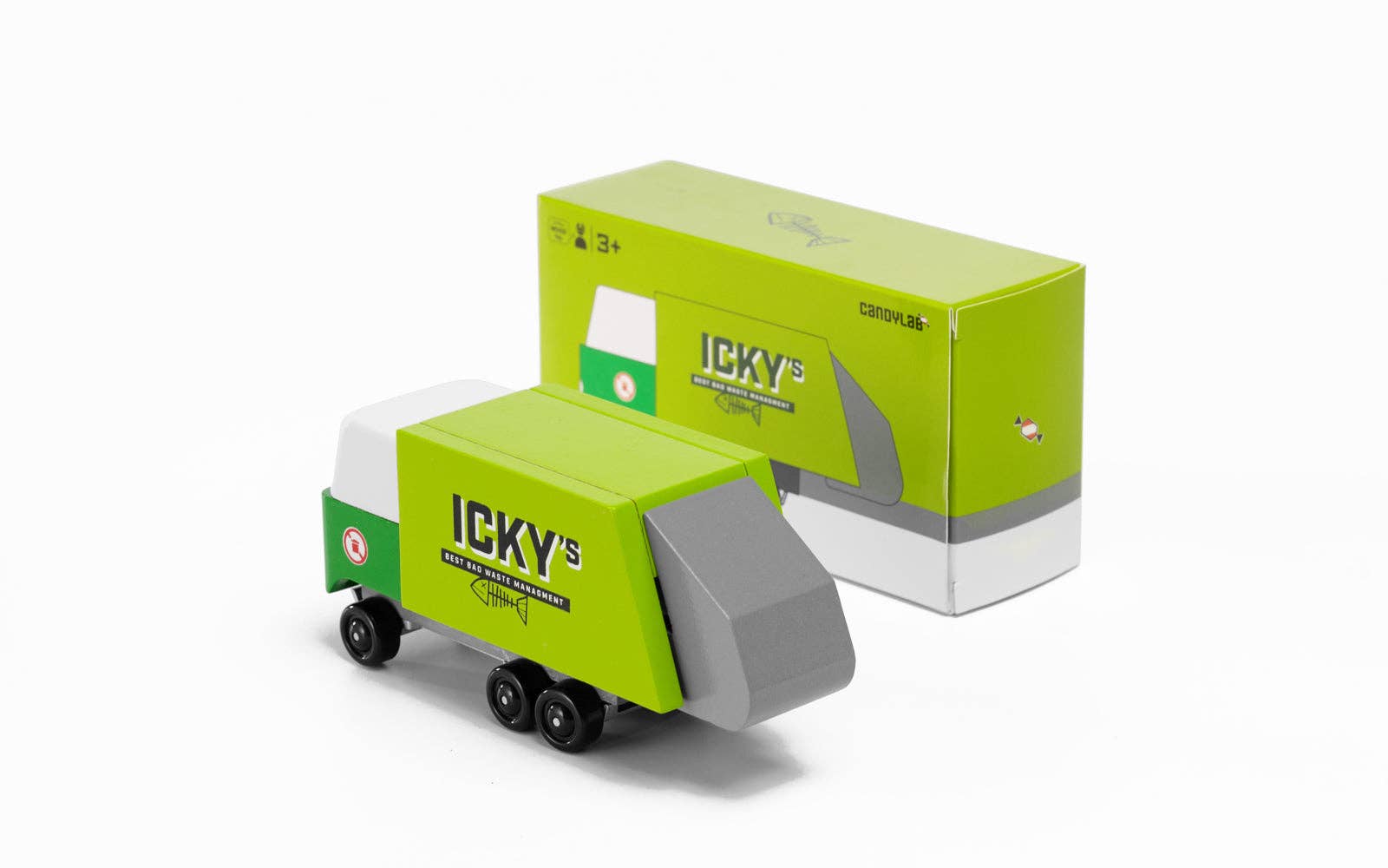 Green toy truck with gray front and white back, next to its packaging on a white background