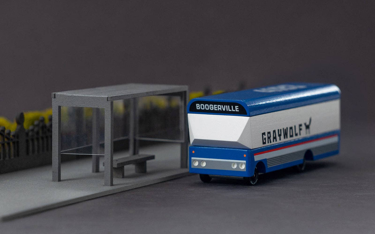 Toy graywolf bus going to 'boogerville' at a bus stop on a grey background