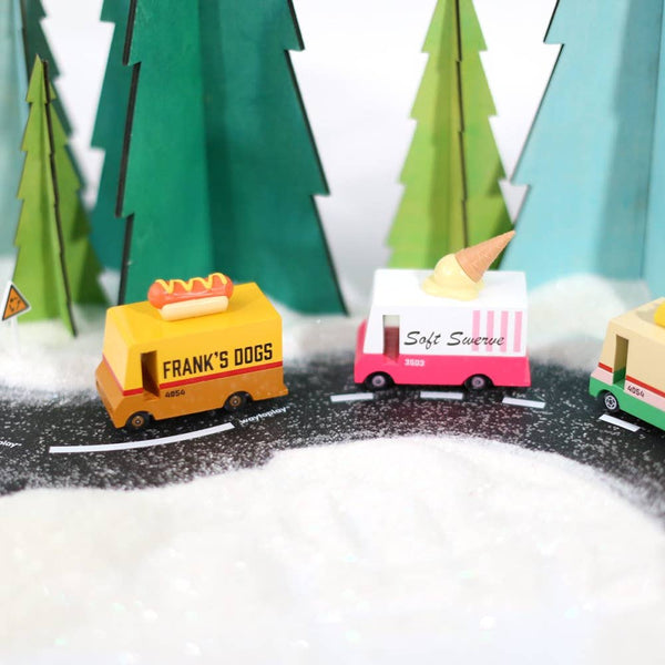 Toy trucks on a miniature road with paper trees in the background