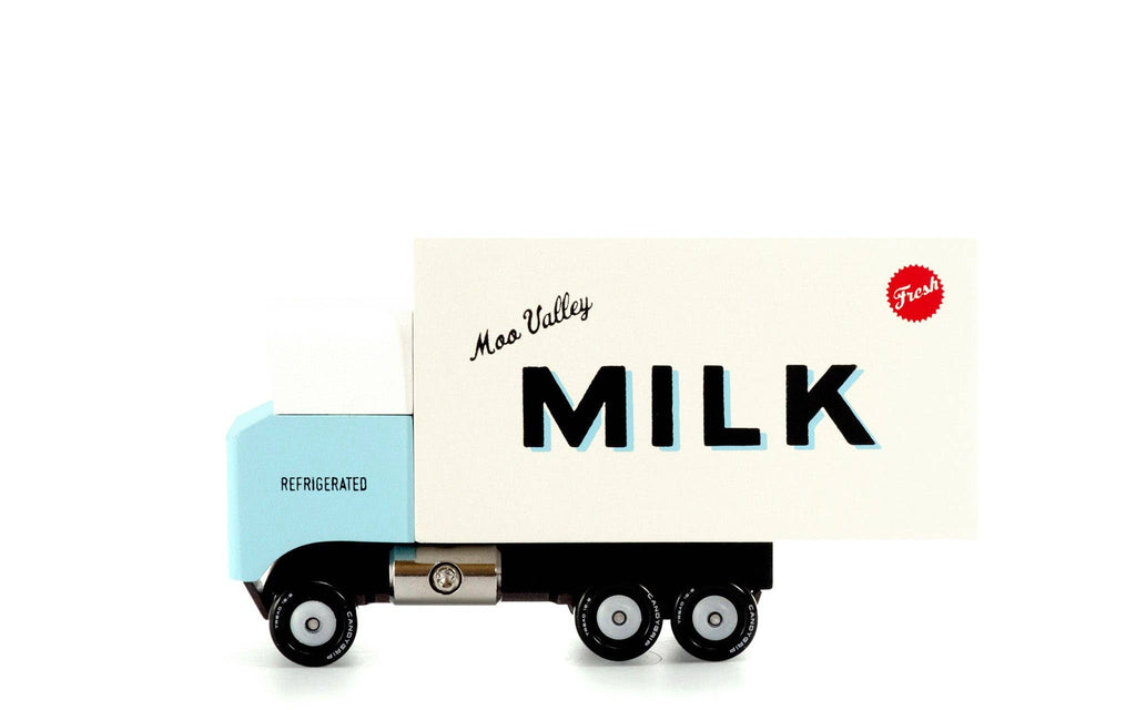A retro-style toy milk delivery truck with a light blue cab and a cream-colored milk container body, featuring 'MILK' and 'Moo Veezy' printed on the side, set against a plain white background.
