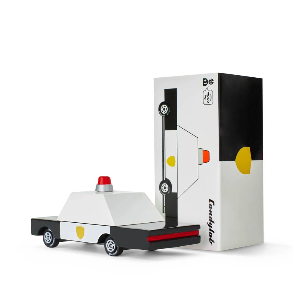 Toy car model of a police vehicle next to its packaging on a white background