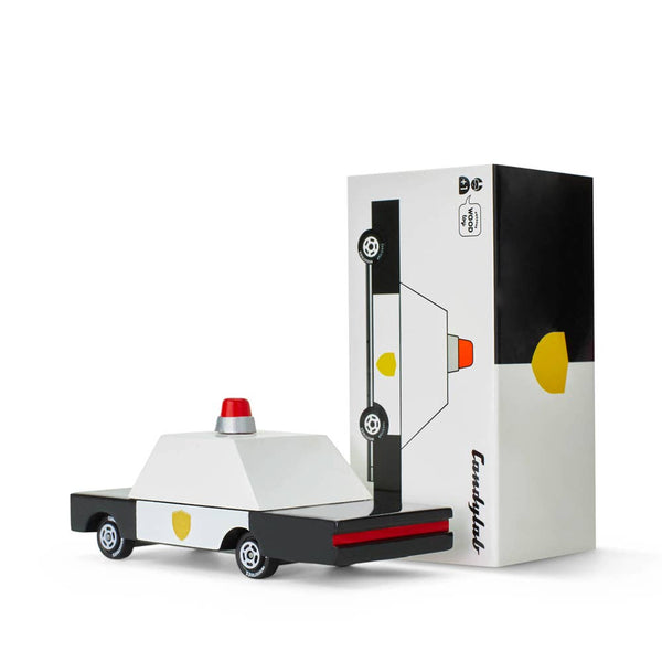 Toy car model of a police vehicle next to its packaging on a white background