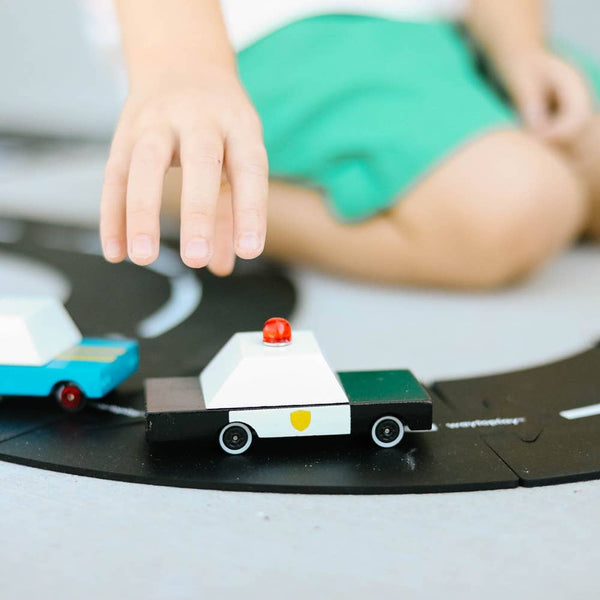 Child playing with toy cars on a road surface