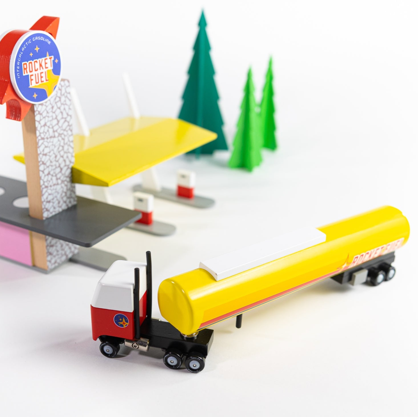 Toy fuel truck with a station and trees on a white background