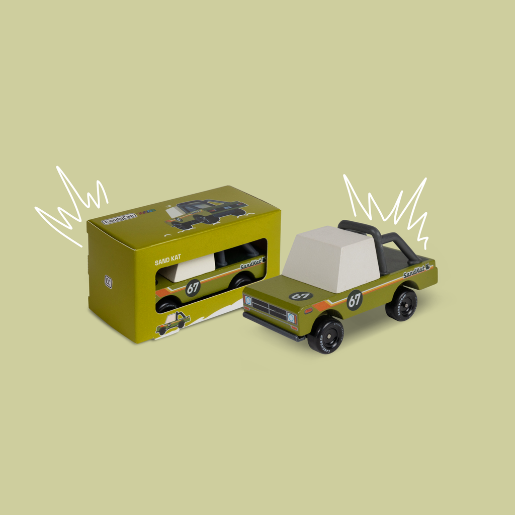 Green toy truck with white top next to its packaging on a beige background
