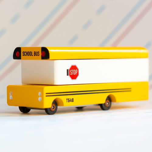 Yellow toy school bus with a stop sign on a white background