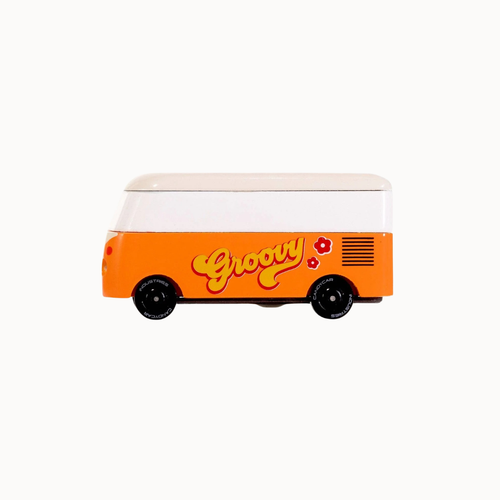 A retro-style toy van with a white upper section and a bright orange lower section, featuring the word 'Groovy' in yellow script with red flowers on the side, set against a plain white background.