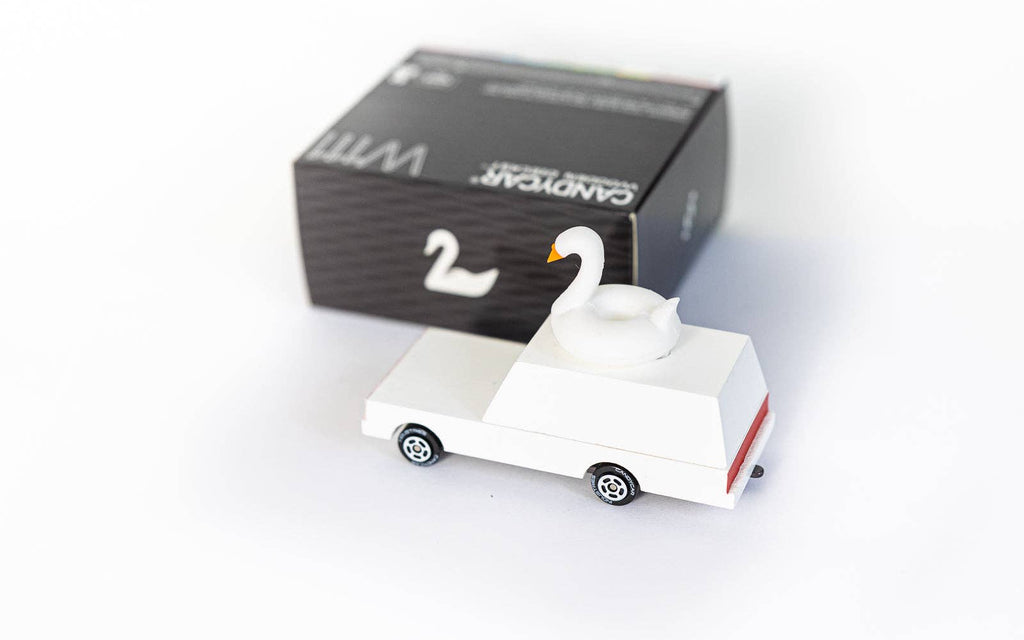White swan-shaped car toy with a black box in the background