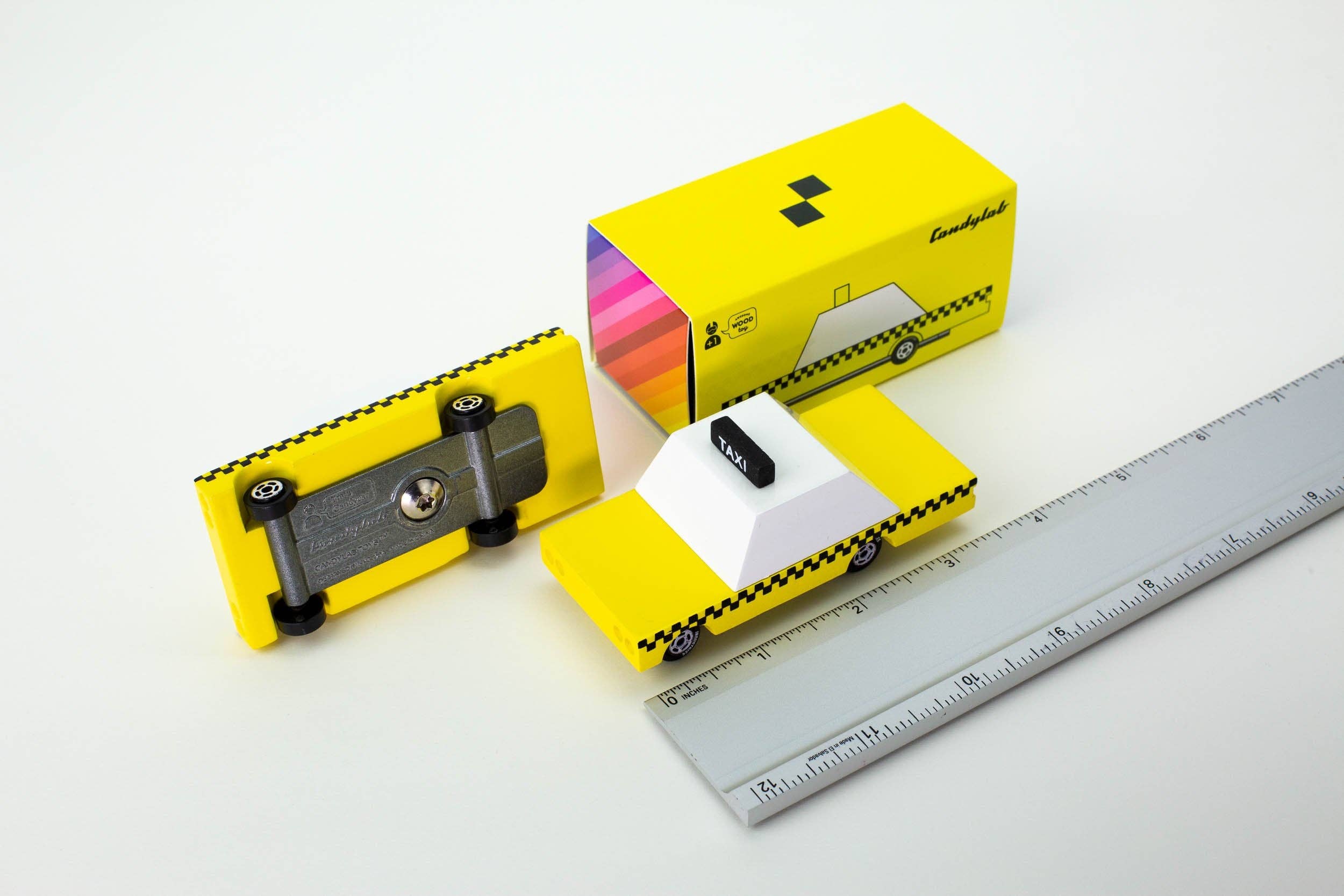 Yellow toy car with a sharpener and packaging on a white background
