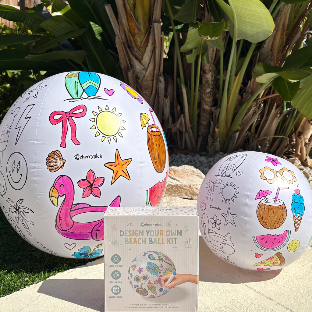 Two design-your-own beach balls with a coloring book kit on a patio background.