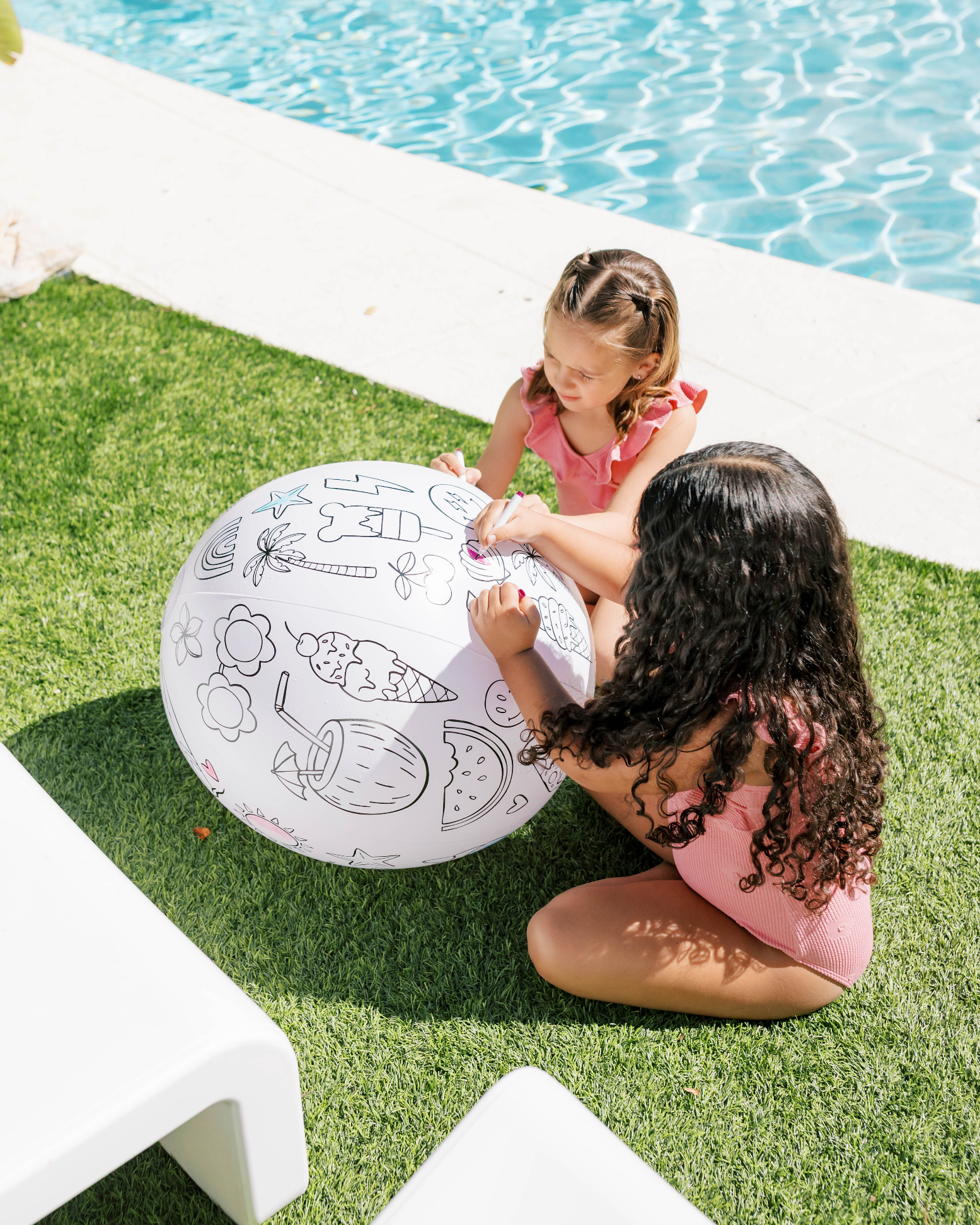 Two children playing with a large inflatable ball by a pool