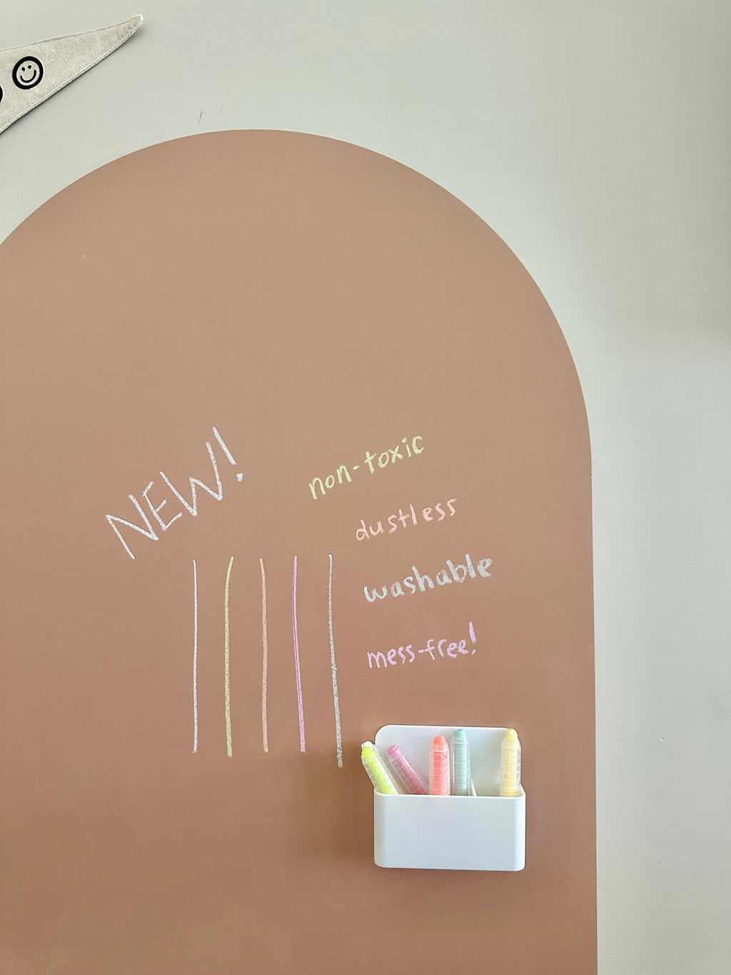 Brown arch-shaped chalkboard with colorful chalk and text on a white wall