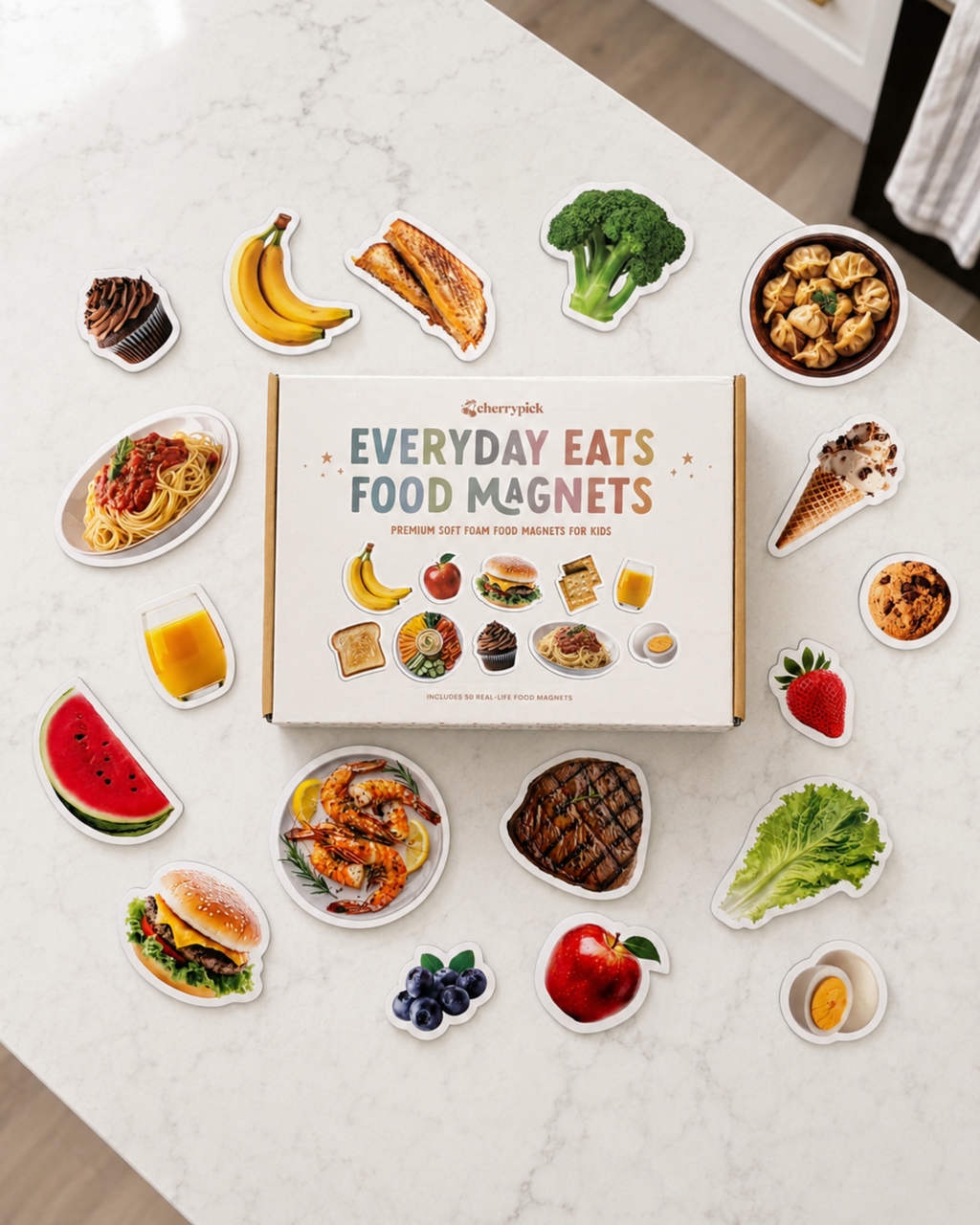Box of Everyday Eats food magnets on a marble countertop with various food-shaped magnets displayed around it.