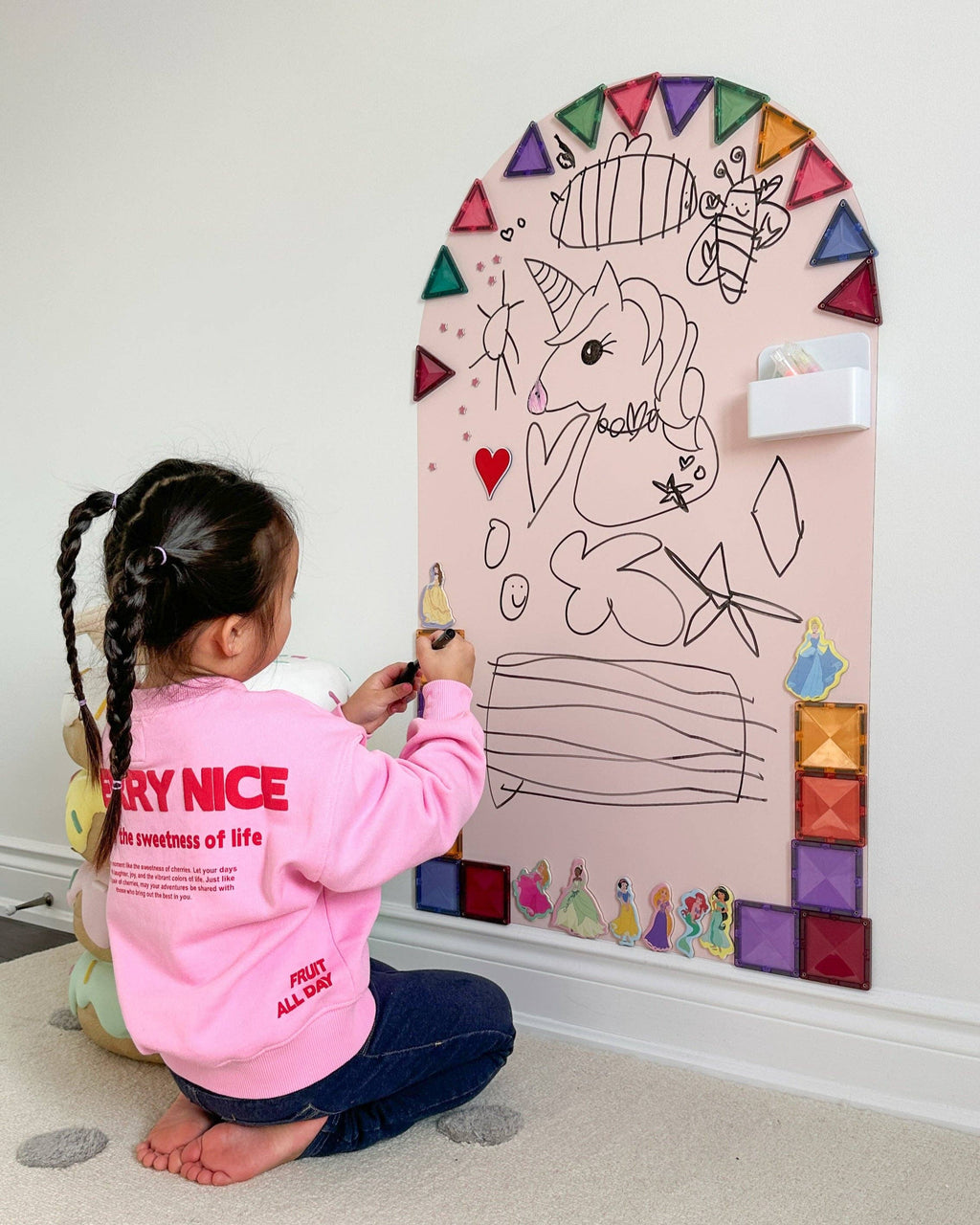 Child drawing on a large mirror with colorful decorations
