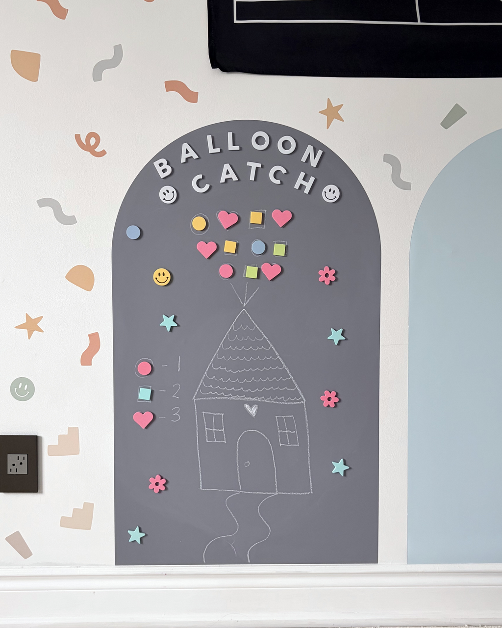 Children's game board with 'Balloon Catch' design on a white wall with decorative elements.
