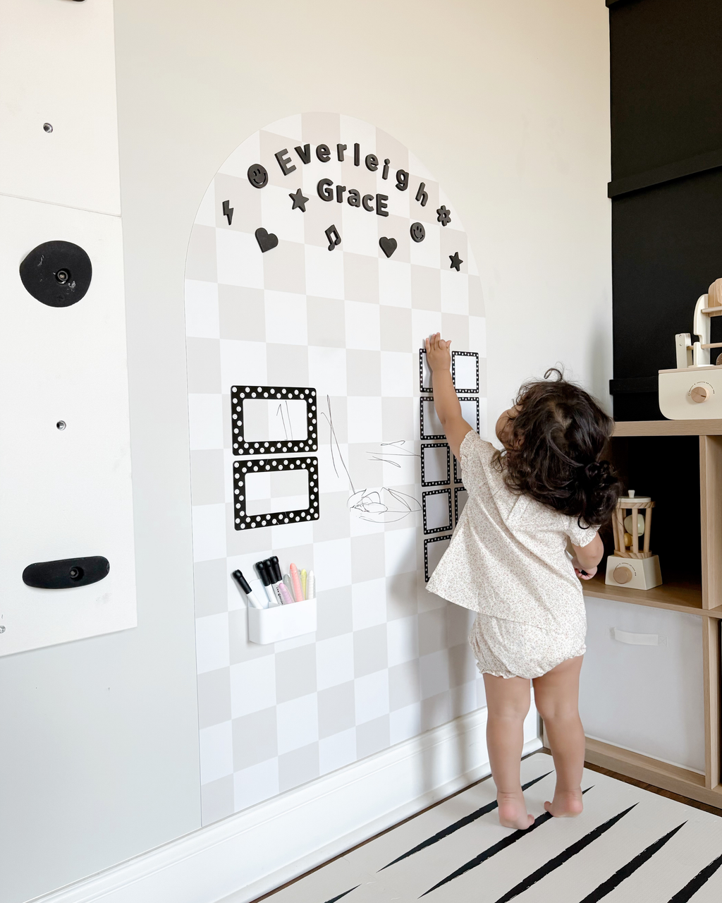 Child interacting with a decorative wall panel in a room.