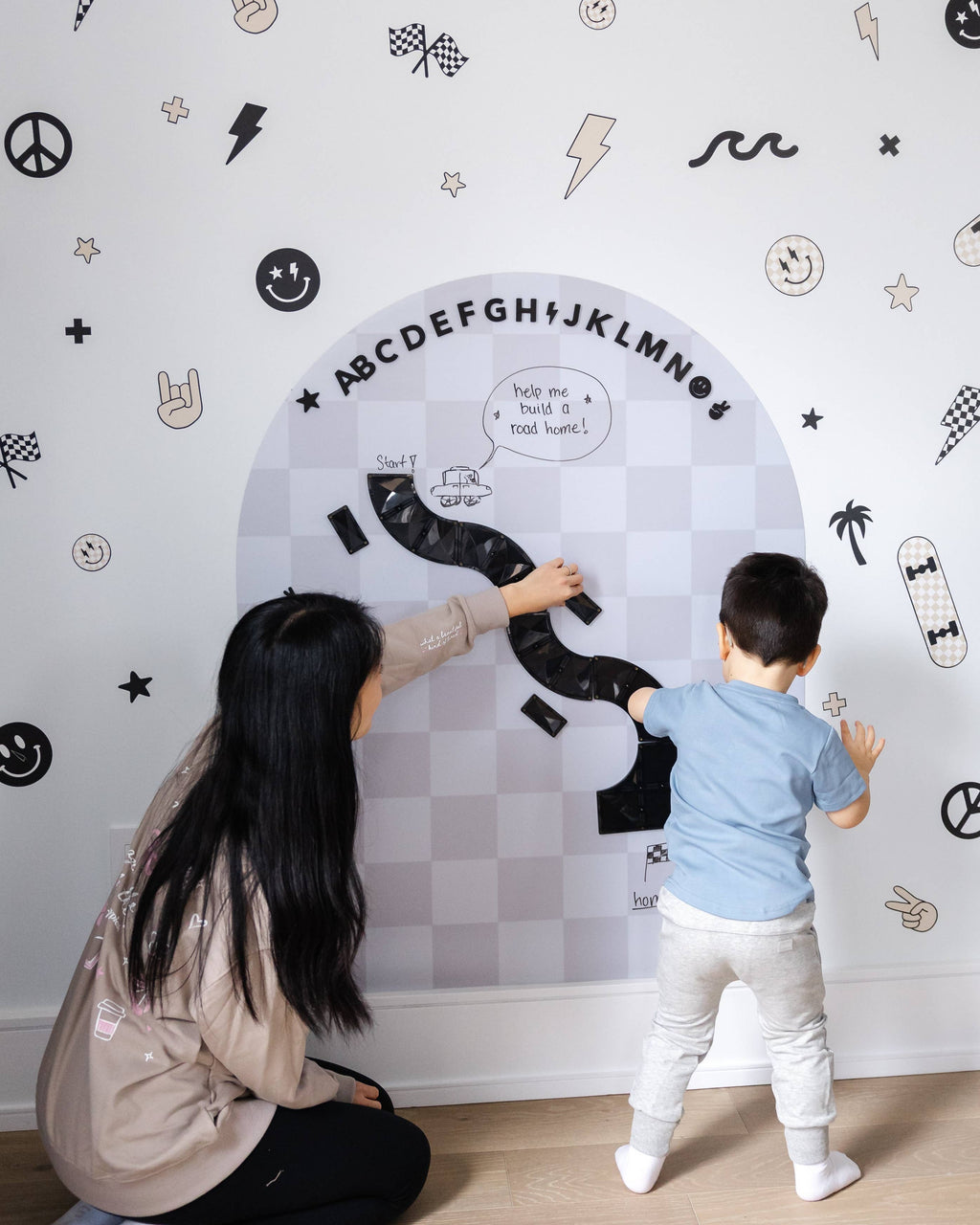 Woman and child interacting with a large alphabet chart on a wall.