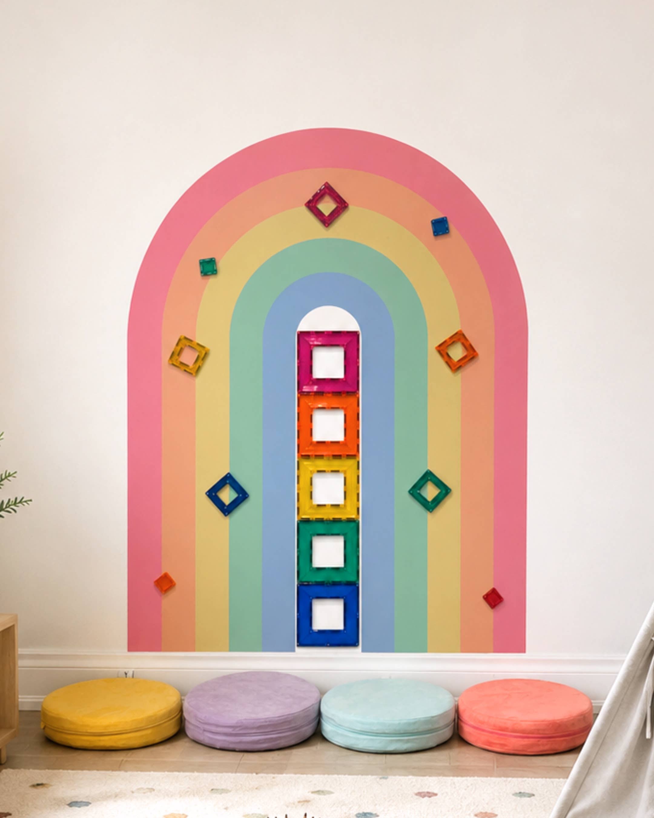 Colorful rainbow-shaped wall decoration with geometric shapes on a white wall.