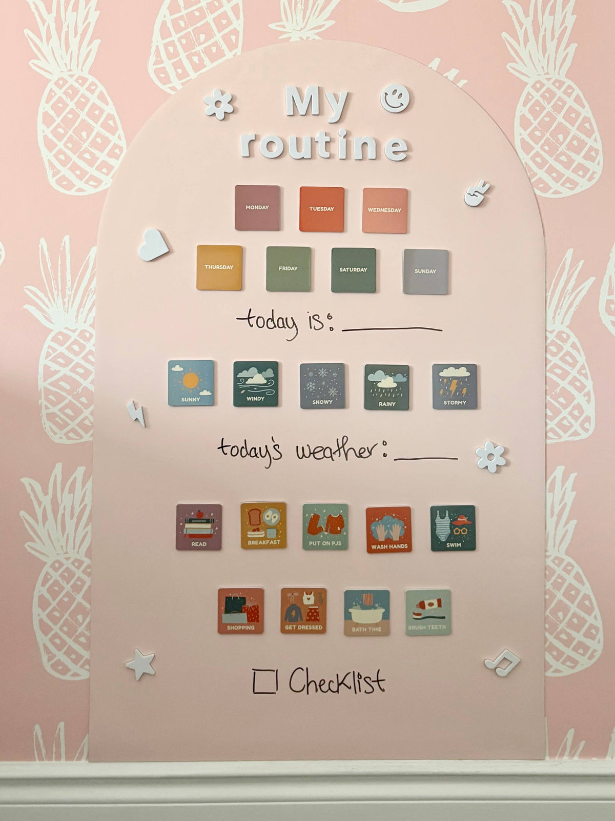 Wall calendar with pineapple designs and weather icons on a pink background