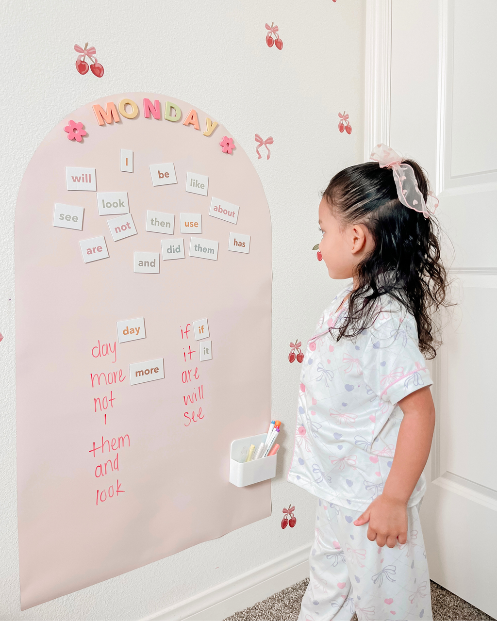 Child looking at a magnetic letter board on a wall with educational words.