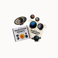 A children's solar system magnets set including a book, a cream drawstring pouch, and several planet magnets, shown on a plain white background.