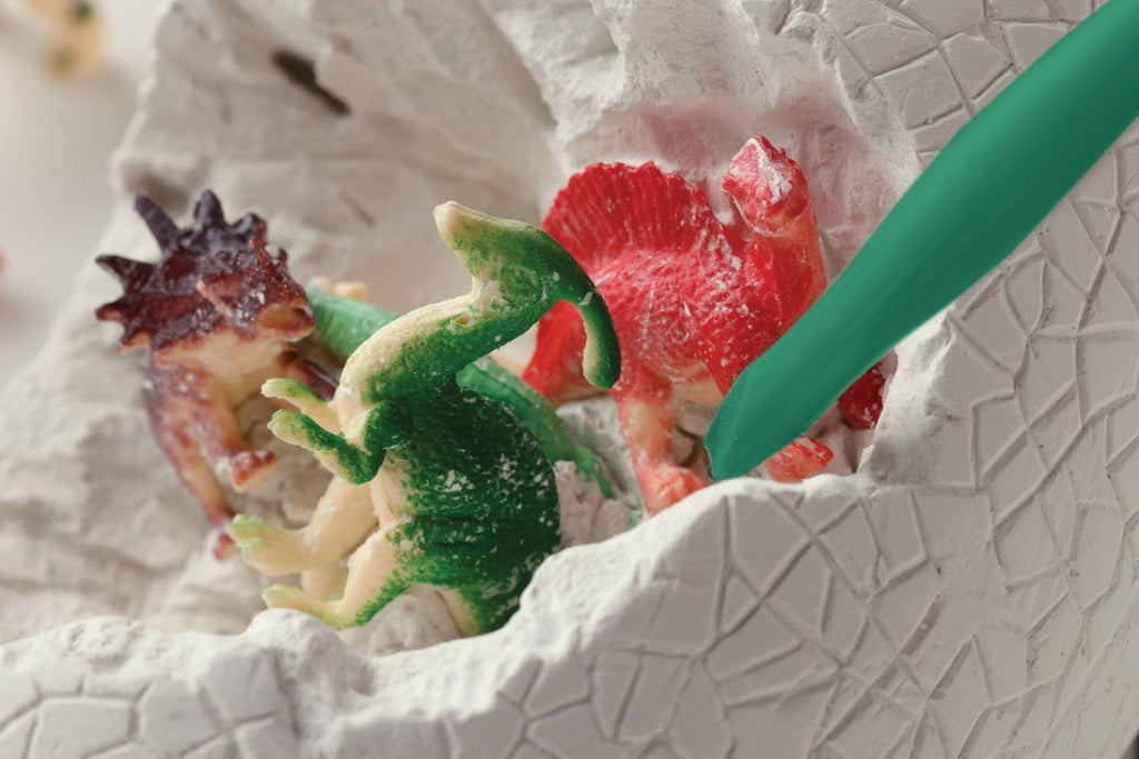 Colorful dinosaur toys in a textured white container with a green tool.