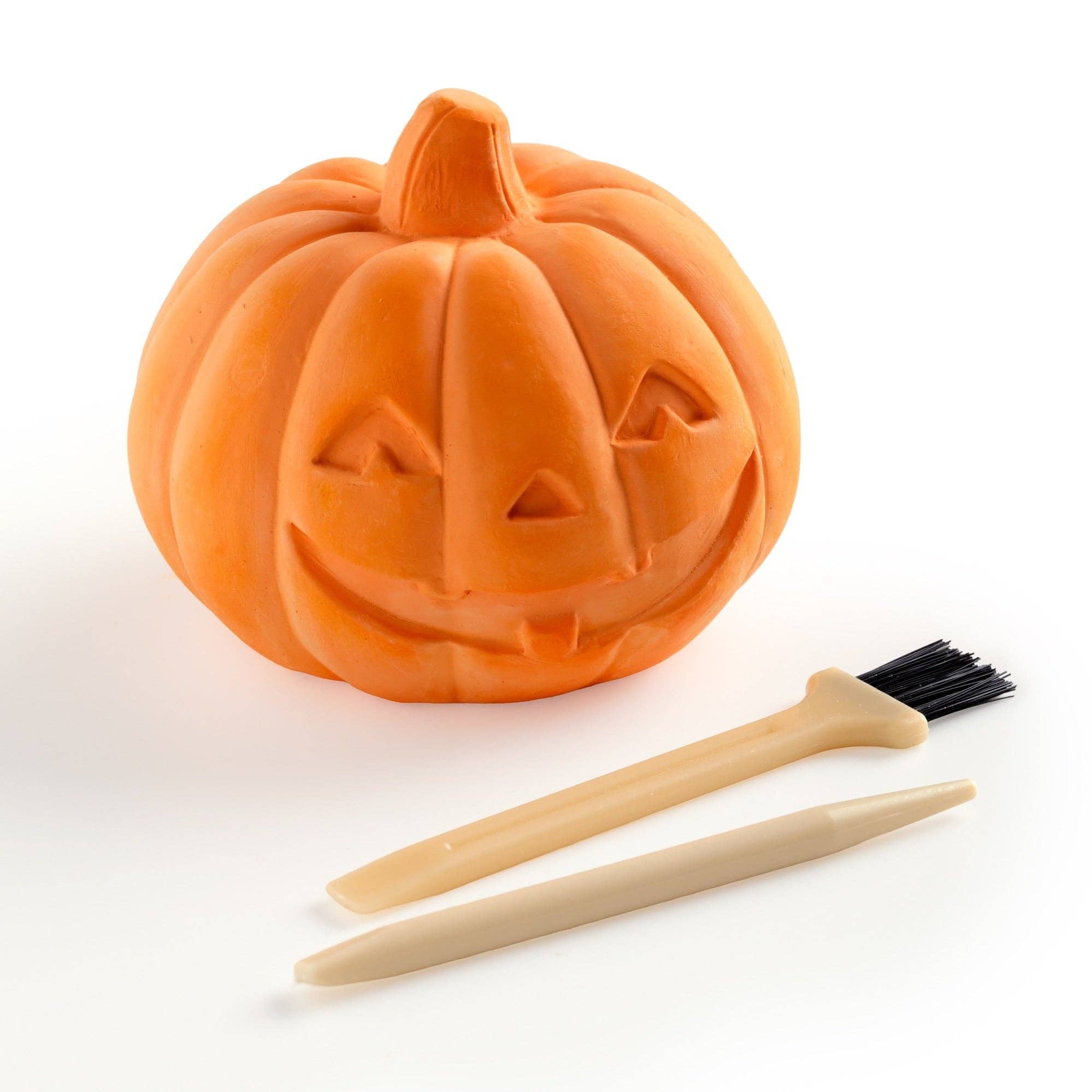 Pumpkin-shaped soap with a face and two wooden tools on a white background
