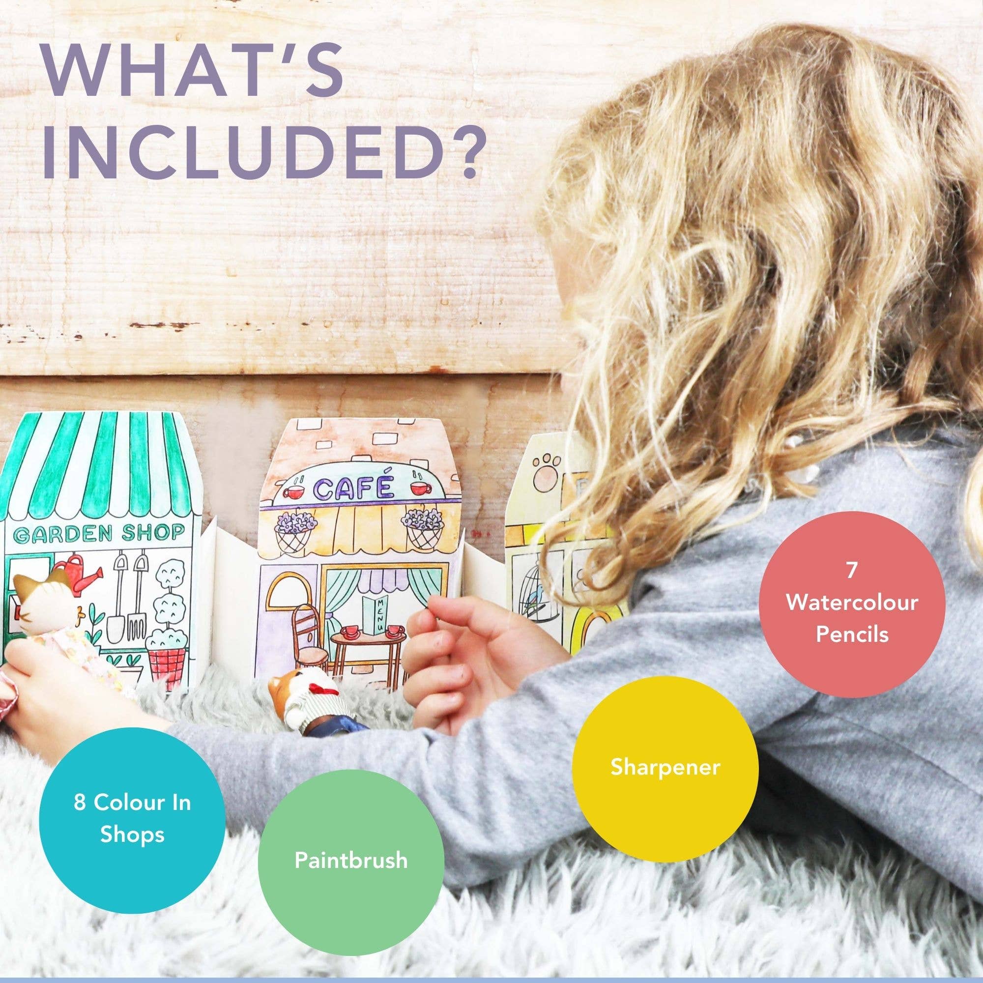 Child playing with toy shops and stationery items on a wooden floor.