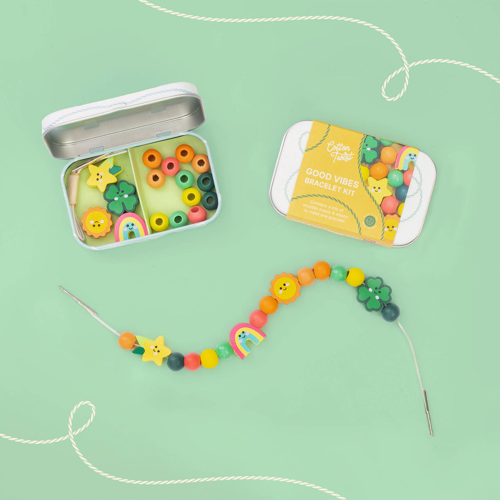 Colorful bead kit with open tin and string on a green background