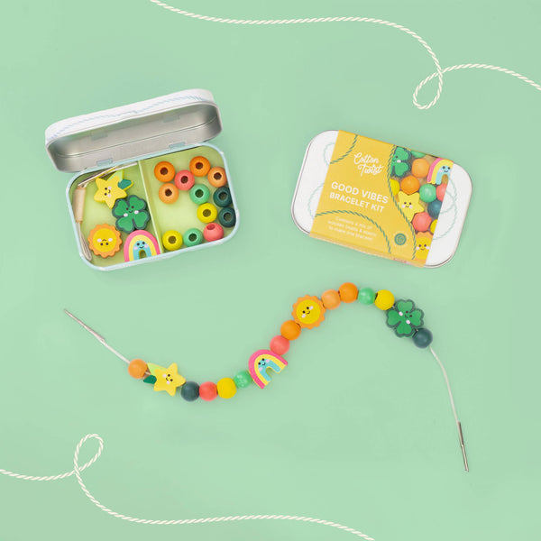 Colorful bead kit with open tin and string on a green background