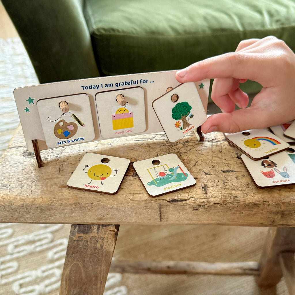 Hand interacting with a set of illustrated cards on a wooden surface