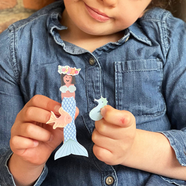 Child holding a paper mermaid and fish toy