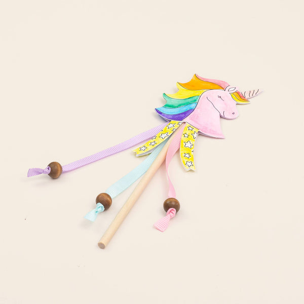 Colorful unicorn toy with wooden sticks on a light beige background