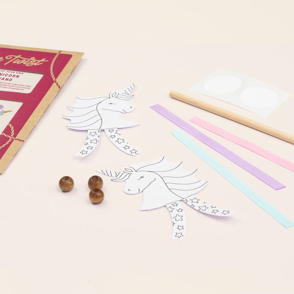 Unicorn-themed craft kit with paper, markers, and beads on a light surface