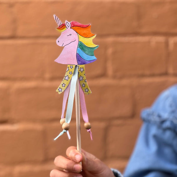 Colorful unicorn toy held by a child against a brick wall background