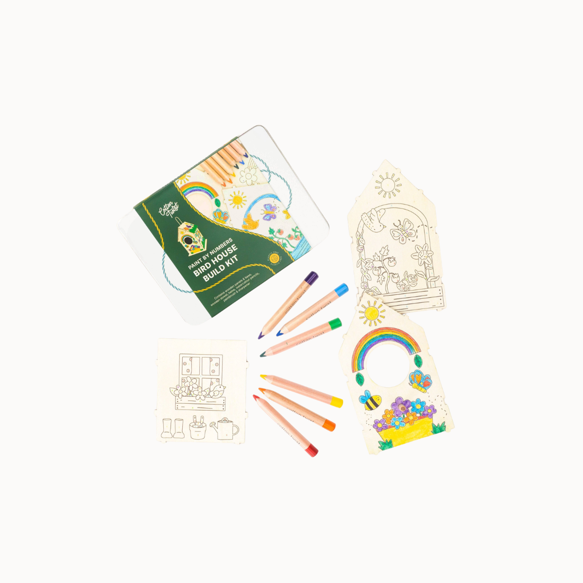 A children's building art kit laid out on a white background, including a printed box, several colored pencils, and two partially filled coloring pages with rainbows and house designs.