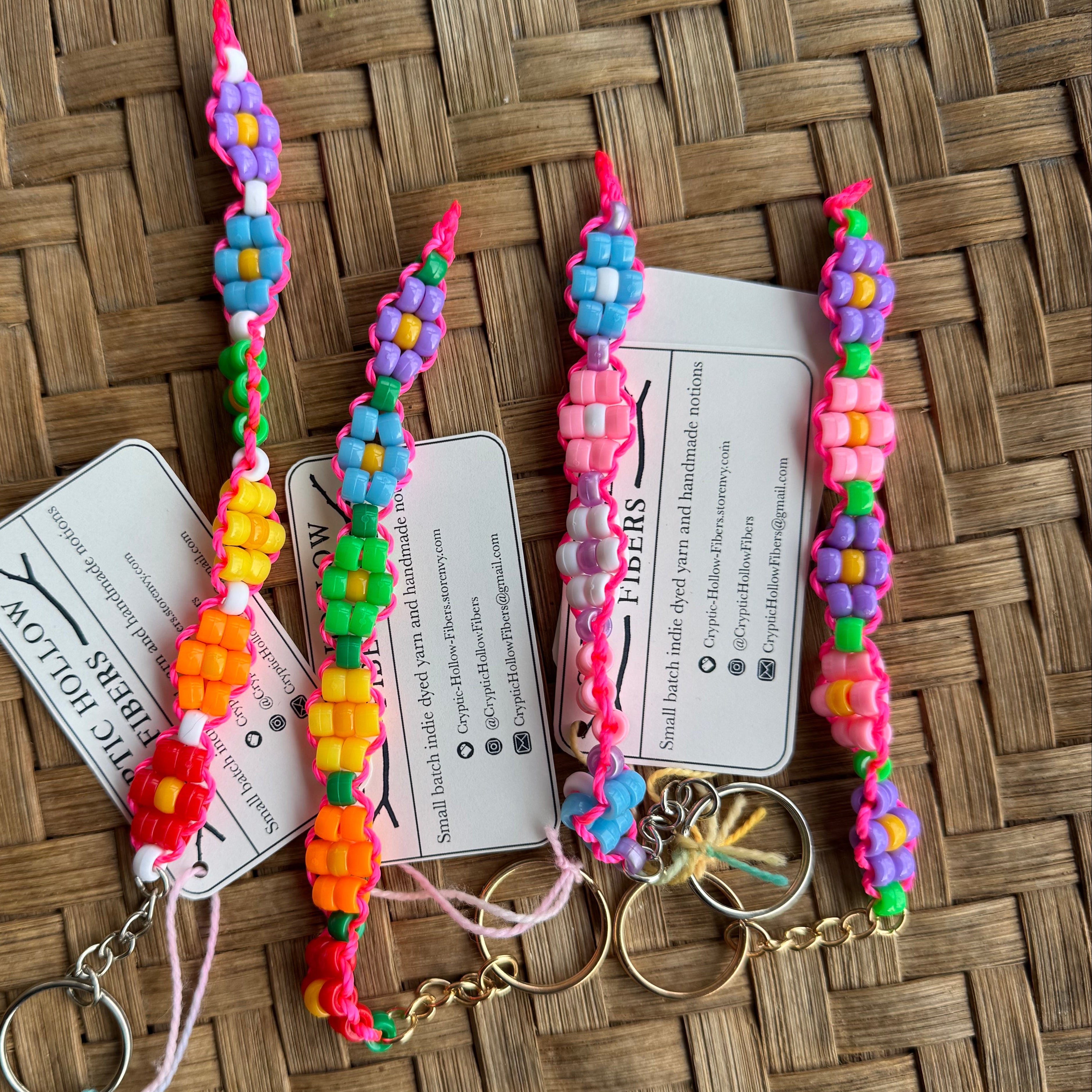 Colorful flower keychains on a woven surface with tags.