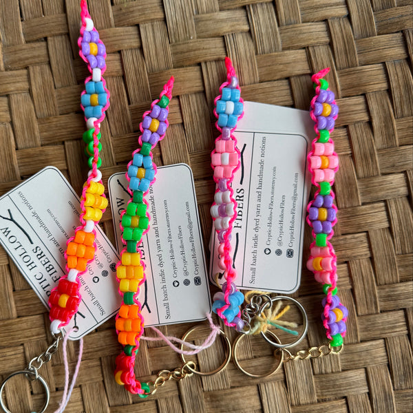 Colorful flower keychains on a woven surface with tags.