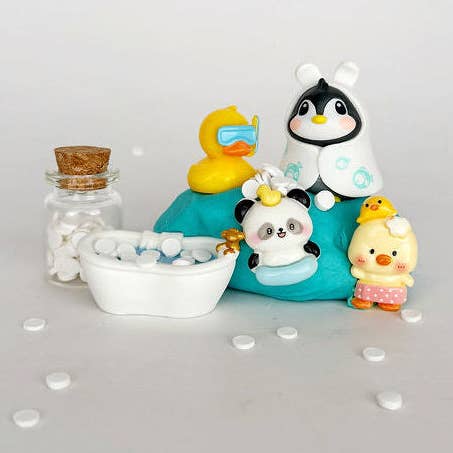 Set of bath toys including a penguin, panda, duck, and rubber duck on a white surface with bubbles.