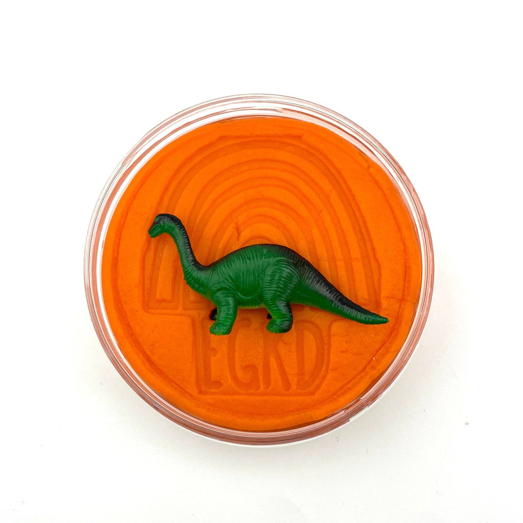 Green dinosaur toy inside an orange container with 'LEGO' branding on a white background